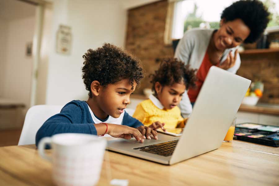 image of Black family a mom and two children using a computer at a coffee table
